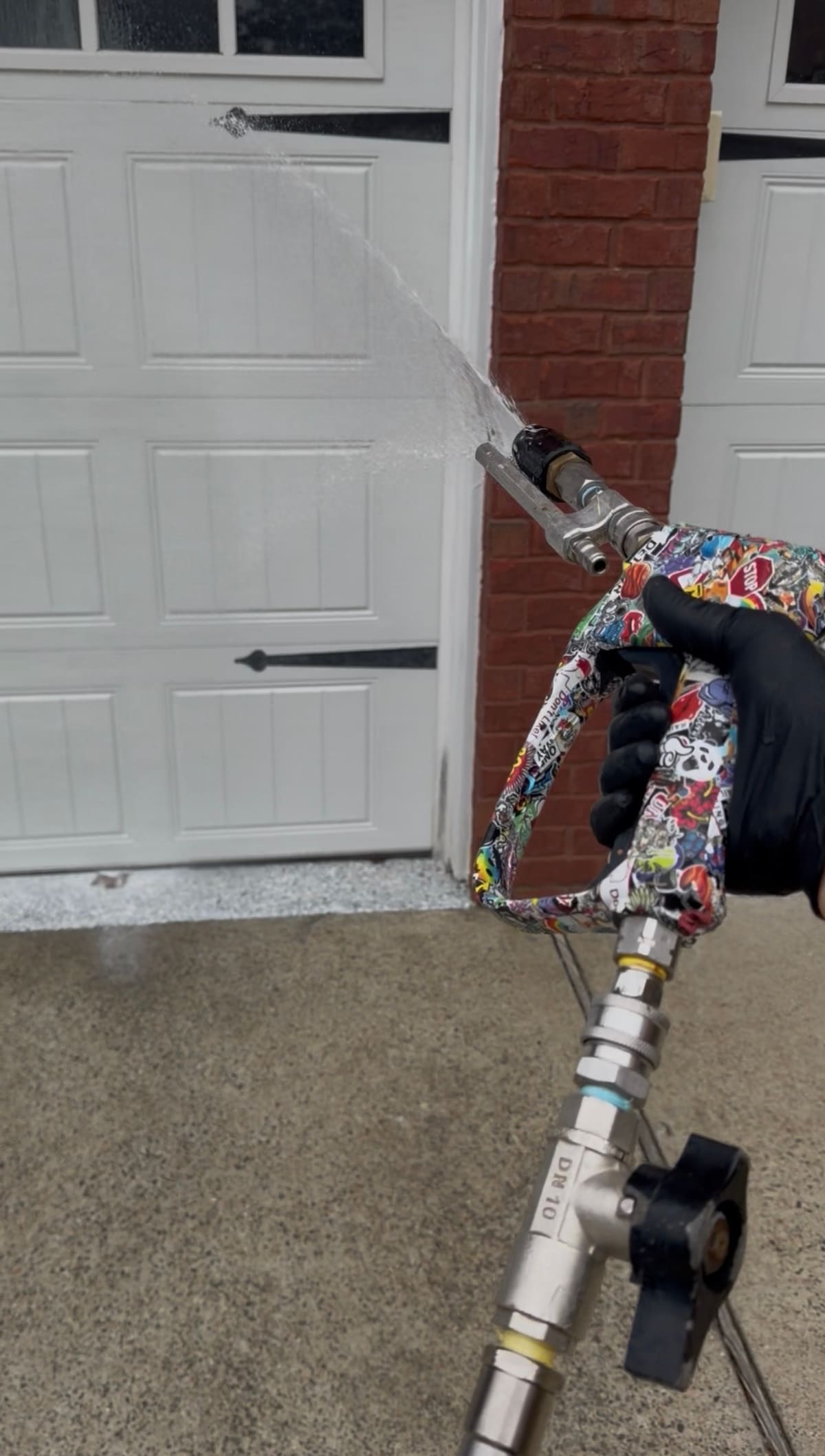 Kevin of KM Property Restorations soft washing the brick beside a white garage door